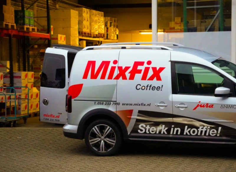 Bezorgbus van Mix-Fix Coffee bij het magazijn met voorraadstellingen op de achtergrond